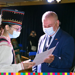 Wicemarszałek Olbryś wręcza dyplom dziewczynie w stroju ludowym.