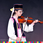 Dziewczyna w stroju ludowym gra na skrzypcach.