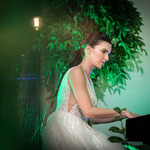 kobieta w białej sukni grająca na fortepianie