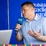 Marek Malinowski udziela wywiadu trzymając niebieski mikrofon
