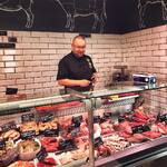Mężczyzna stoi za ladą sklepową z mięsami