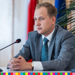 Radny Paweł Wnukowski siedzi przy stole przed mikrofonem