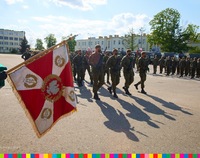 Defilada żołnierzy. Po lewej widać sztandar z białymi i czerwonymi barwami z orłem