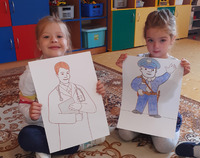 Dwie dziewczynki w przedszkolu prezentują rysunki.