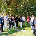 grupa młodych ludzi biorąca udział w projekcie pozuje do zdjęciawśród zieleni