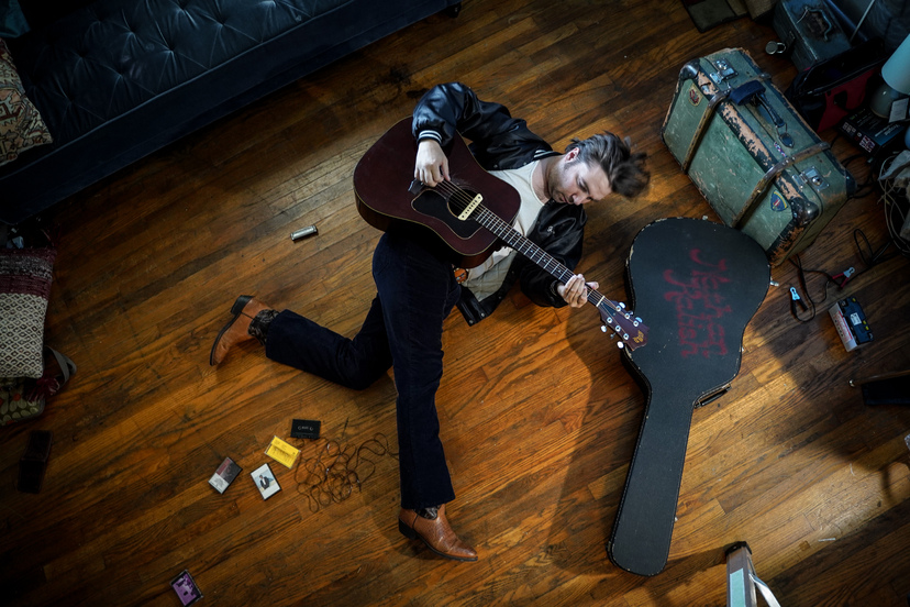 Mężczyzna leży na podłodze i gra na gitarze