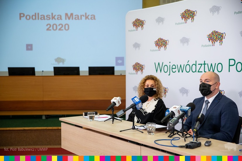 Magdalena Łyżnicka-Sanczenko oraz marszałek Artur Kosicki siedzą za stołem zastawionym mikrofonami