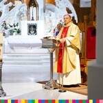 Arcybiskup Józef Guzdek stoi za mównicą w prezbiterium