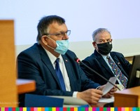 Dwóch mężczyzn w masce siedzących przy mikrofonie. Z prawej wicemarszałek Olbryś