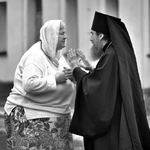 Kobieta rozmawia z księdzem prawosławnym.