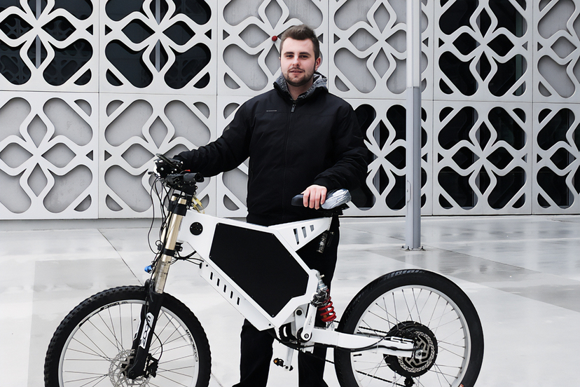 Damian Orzechowski pozuje do zdjęcia ze swoim rowerem elektrycznym