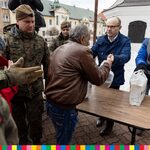 Marszałek Artur Kosicki wręcza paczki świąteczne potrzebującym. Obok widoczni terytorialsi w mundurach