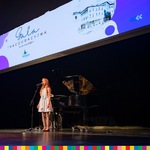 Dziewczynka na scenie przed mikrofonem, u góry baner z napisem: Gala inauguracyjna 