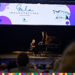 Chłopiec na scenie, gra na pianinie, u góry baner z napisem: Gala inauguracyjna 