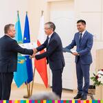 Trzech mężczyzn na tle flag Polski, Kazachstanu i Unii Europejskiej