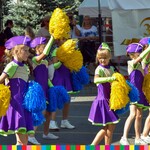 Dziewczynki z zespołu tanecznego w kolorowych ubraniach z pomponami w dłoniach.