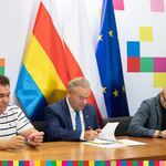 Trzy osoby w trakcie podpisywania umów.