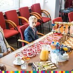 Chłopiec siedzi za stołem na którym są ułożone medale i szachy