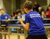 Chłopak z koszulką sportową z napisem Dojlidy Białystok gra w tennisa stołowego
